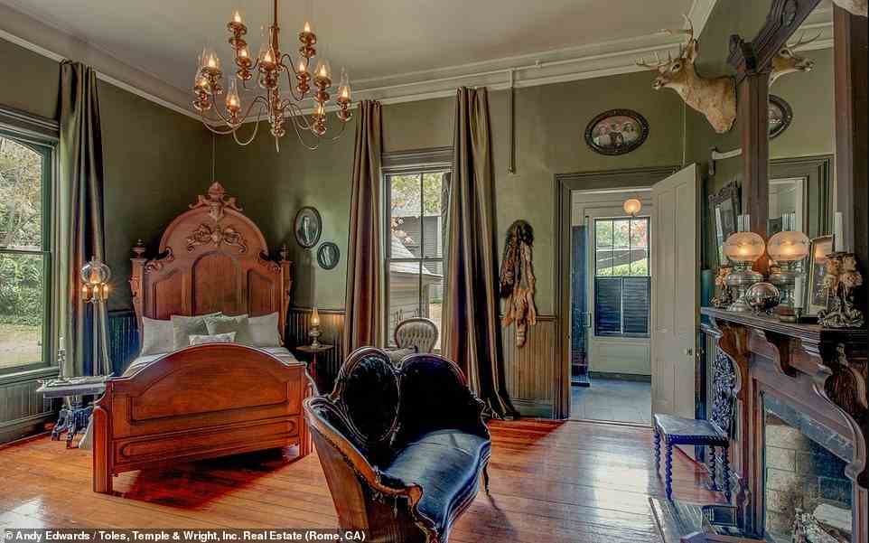 Jedes Zimmer verfügt über ein antikes Bett mit einem kleinen Sitzbereich mit salbeifarbenen Wänden und dunkler Vertäfelung