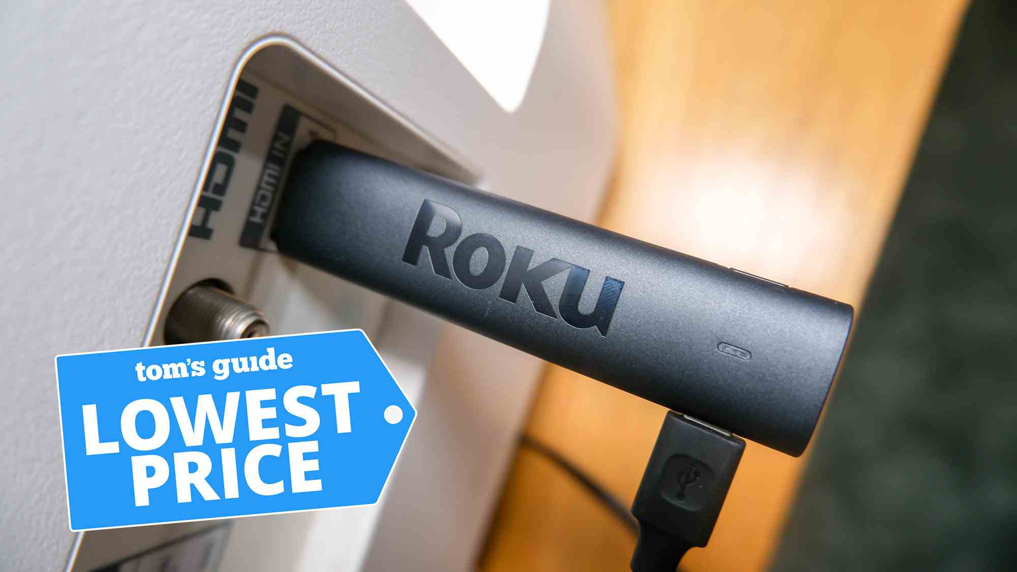 Der Roku Streaming Stick 4K, der an einen HDMI-Anschluss angeschlossen ist, mit einer Tom's Guide Lowest Price-Grafik oben
