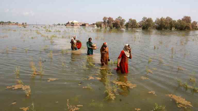 Pakistanische Frauen waten am Freitag, den 2. September 2022, während sie im Distrikt Shikarpur in der Provinz Sindh in Pakistan Zuflucht suchen, durch Hochwasser. Bild: AP
