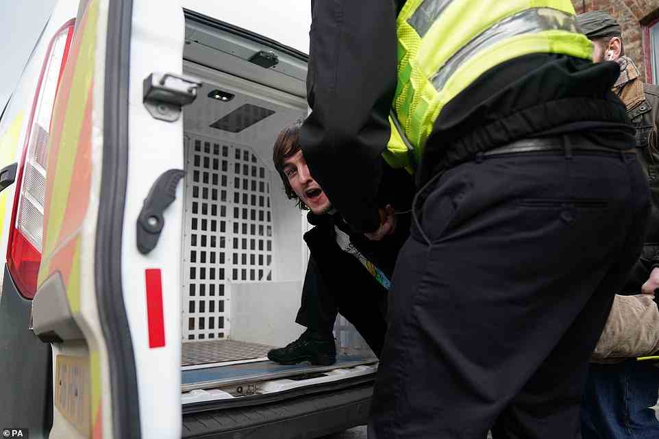 The 23-year-old is put into a police van by officers before being taken away from the scene