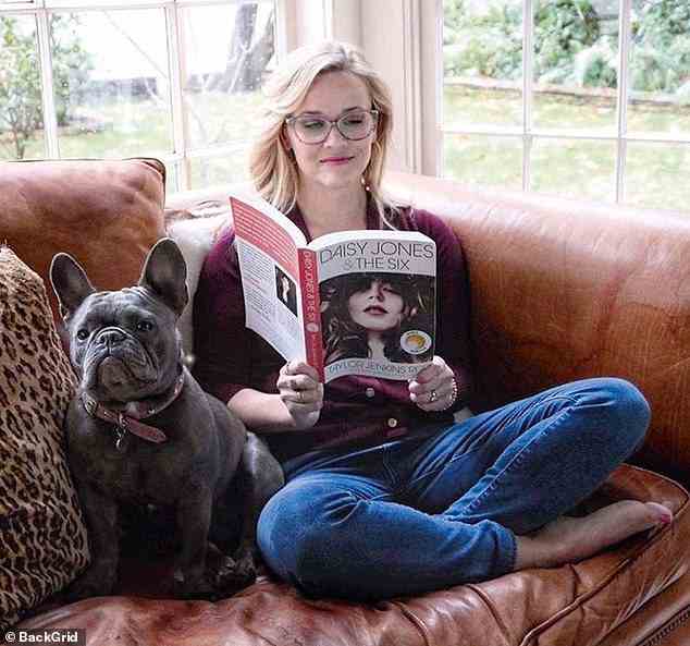 Reese with dog Pepper in 2019, at home,  reading one of the novels she adapted for TV
