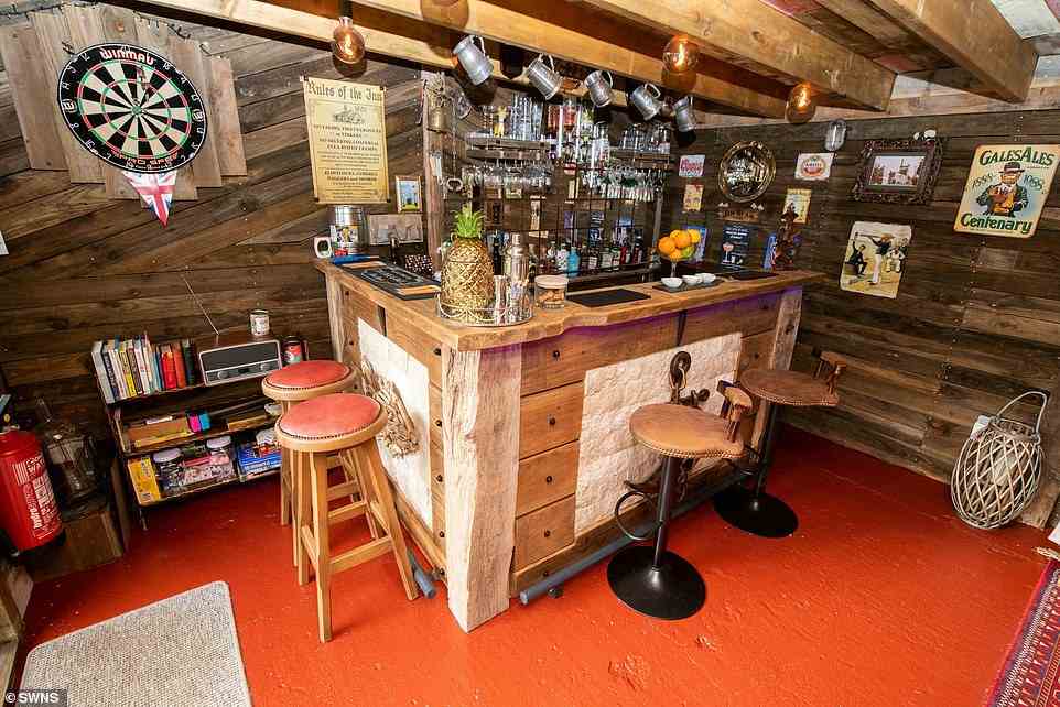 Fotos des Kneipenschuppens zeigen seine gut ausgestattete Bar mit Hockern, Krügen, die an Haken an der Decke hängen, und einer großen goldenen Ananas