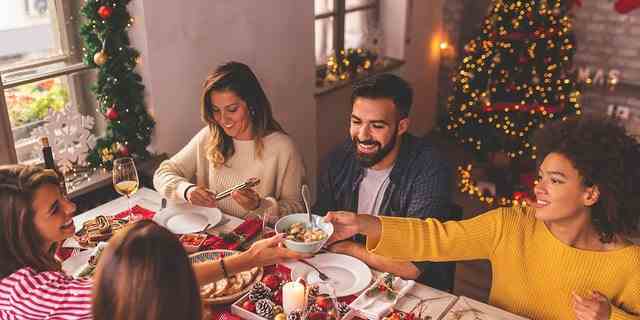 Freunde, die Spaß haben, Weihnachten zu feiern, am Tisch zu sitzen, zu essen, Wein zu trinken und Spaß zu haben, während sie in den Winterferien Zeit miteinander verbringen