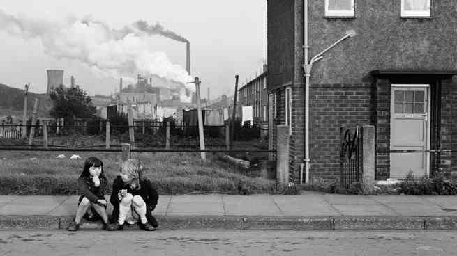 Zwei Kinder sitzen zusammen auf einem Bürgersteig in einem Viertel, in Schwarz-Weiß