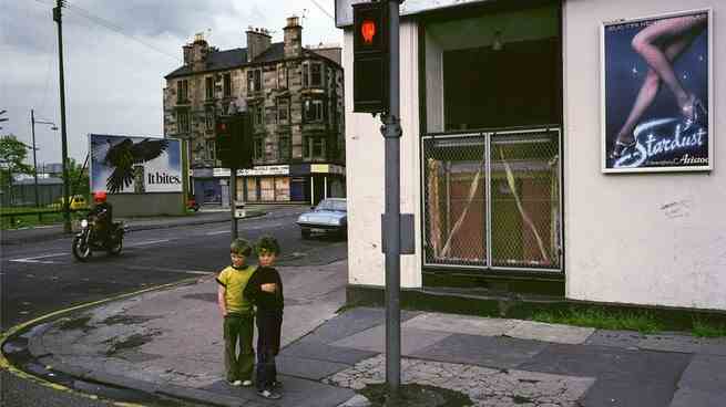 Zwei kleine Kinder standen in den 1980er Jahren zusammen an einer Straßenecke in Glasgow