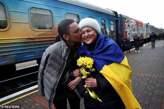 Anastasia küsst ihre Mutter Oksana, als sie heute Morgen mit dem ersten Zug nach Russlands militärischem Rückzug von Kiew nach Cherson kommt, am Hauptbahnhof in Cherson, Ukraine