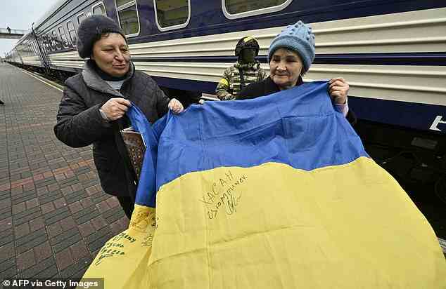 Anwohner halten eine ukrainische Flagge auf dem Bahnsteig neben dem ersten Zug von Kiew nach Cherson