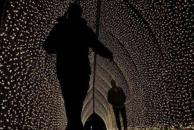Menschen gehen am 15. November 2022 auf Kews Weihnachtslichtweg in den Royal Botanic Gardens in Kew, London, durch einen Tunnel aus Lichtern.