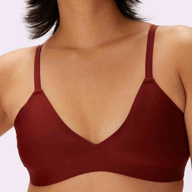 A woman modeling the maroon Parade Smooth Lift Triangle Bralette on a grey background