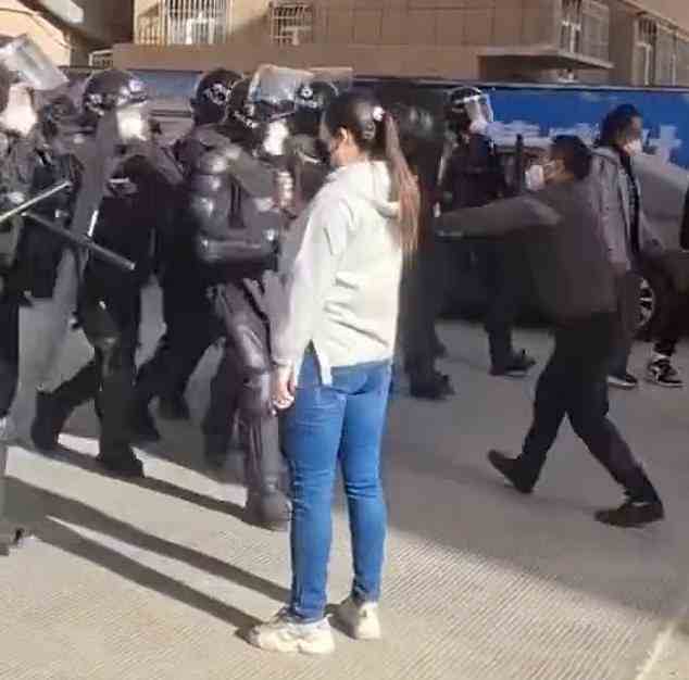 A female Chinese demonstrator stares down riot cops in video thought to have been taken in the city of Pingxiang, also at the weekend