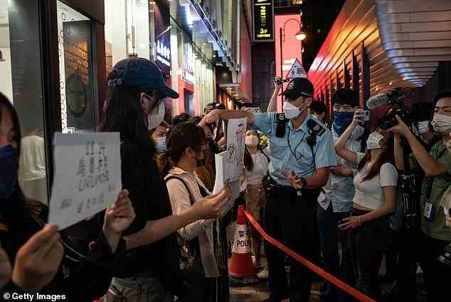 People hold signs in protest of COVID restriction in mainland as police setup cordon during a vigil in the central district on Monday night in Hong Kong, China.