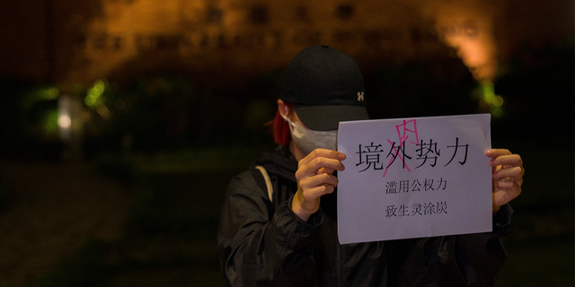 Ein Demonstrant hält ein Papier hoch, auf dem steht "Keine ausländischen Streitkräfte, sondern interne Forces" und "Der Missbrauch der Regierungsmacht stürzt die Menschen in Elend und Leid" während einer Versammlung an der Universität von Hongkong.