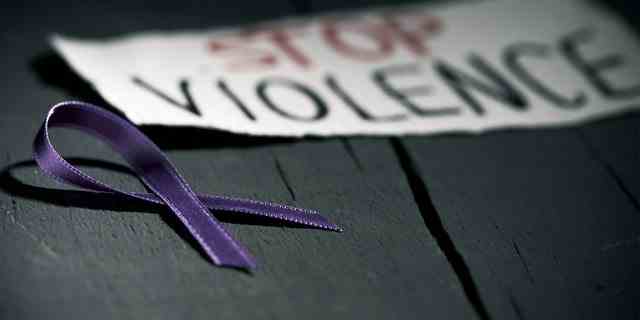 Ein lila Band liegt neben einem Schild, das auf häusliche Gewalt aufmerksam macht.