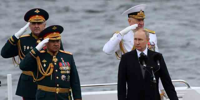 Der russische Präsident Wladimir Putin, vorne rechts, Verteidigungsminister Sergei Schoigu, links, und der Oberbefehlshaber der russischen Flotte Nikolai Jewmenow, hinten rechts, an Bord eines Bootes während der Navy Day Parade am 31. Juli 2022 in Sankt Petersburg, Russland.