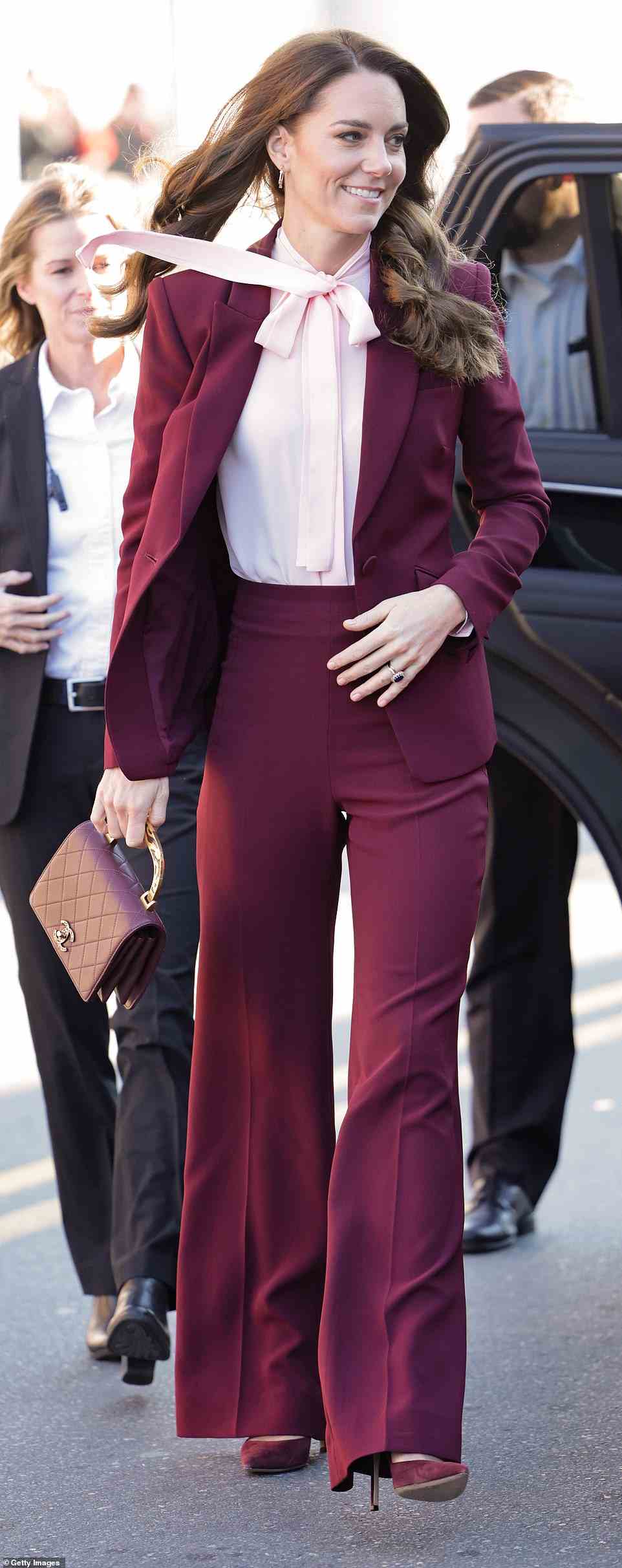 The mother-of-three donned a pair of $534 high-waisted maroon trousers and a matching $2,190 blazer - which is currently sold out in the color Kate wore - made by the British luxury fashion house, as well as a pink tie-neck blouse underneath