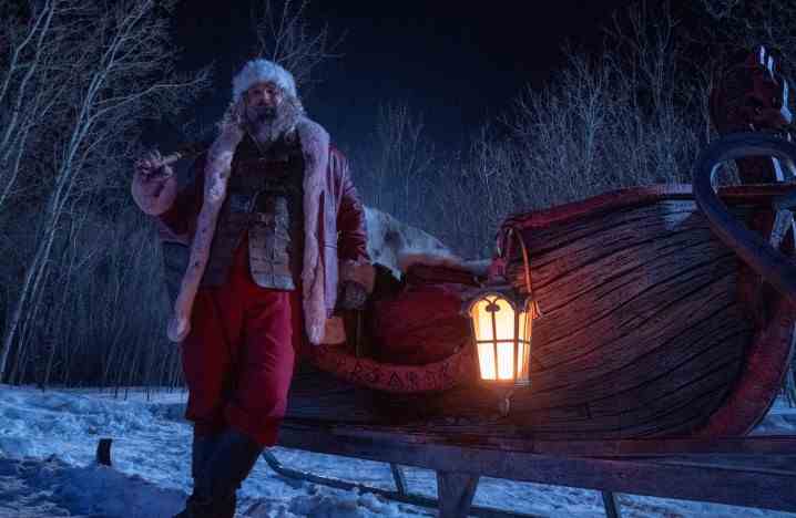 David Harbour, als Weihnachtsmann verkleidet, lehnt an einem Schlitten.