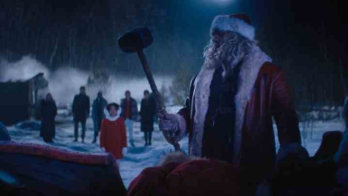David Harbour, als Weihnachtsmann verkleidet, hebt einen Vorschlaghammer von einem Schlitten.