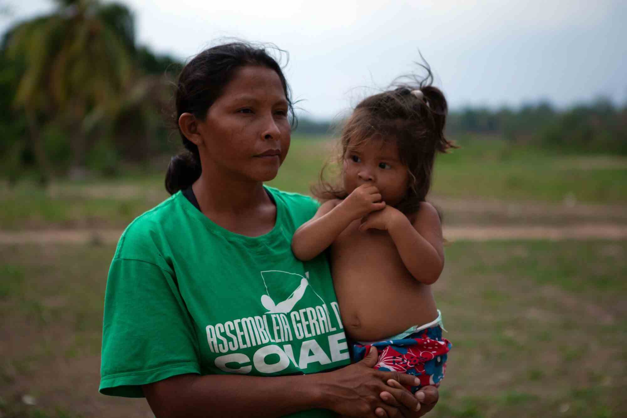 Eine Frau mit dunklem Haar und grünem T-Shirt hält ein junges Mädchen 