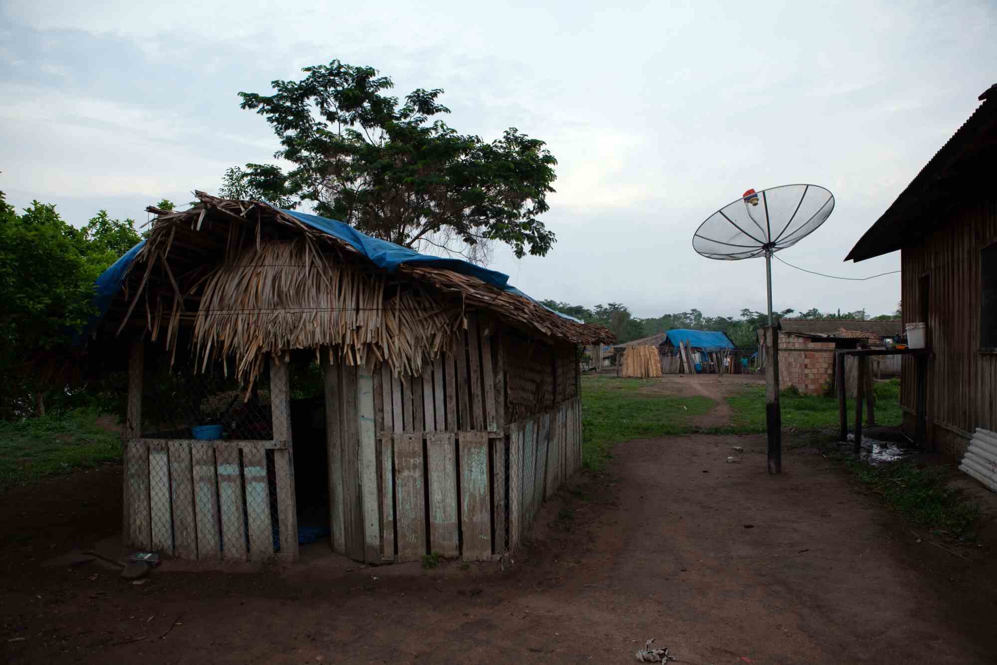 Ein hüttenartiges Haus in einem Dorf mit einer großen runden Antenne in der Nähe 
