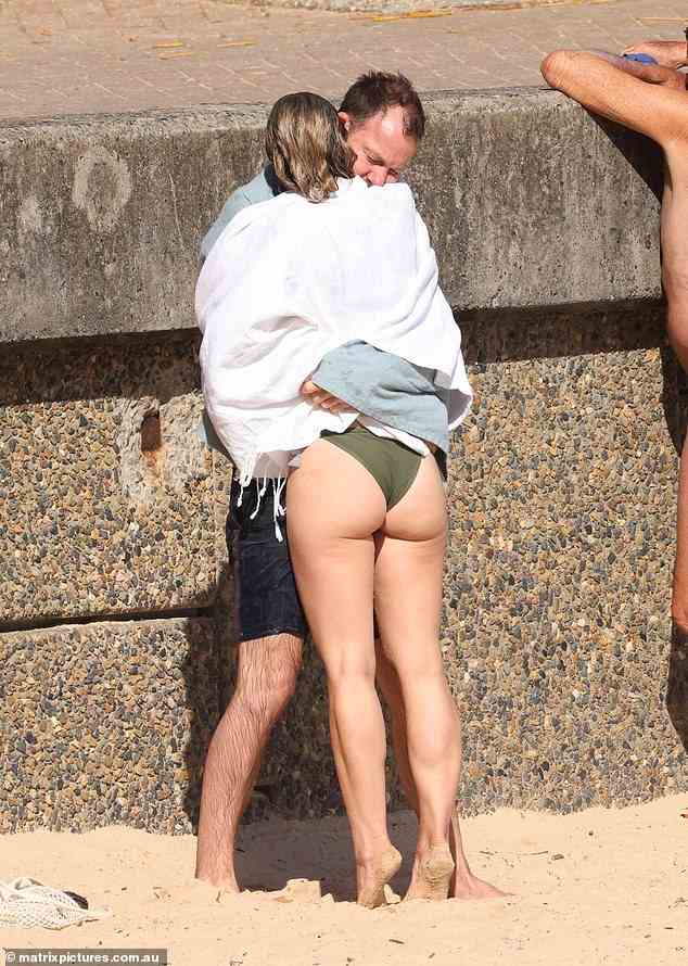Galafassi is pictured with his arms wrapped around Shannon Egan at Manly Beach on Wednesday morning