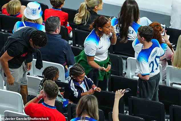 Paige Milian, fiancee of Raheem Sterling of England, speaks with Phil Foden's younger brother in the stands ahead of the England v France match