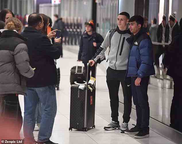 Phil Foden poses for a picture with a fan after arriving at Manchester Airport on Sunday night