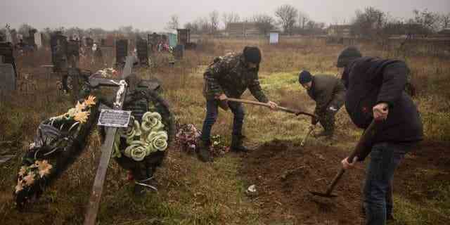 Ukrainische Einwohner und Beamte exhumieren die Leiche eines 16-jährigen Mädchens und sieben weiterer Männer, die von russischen Streitkräften getötet und am 29. November 2022 in der Stadt Pravdyne am Stadtrand von Cherson begraben wurden.