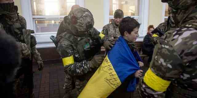 Ein Junge lässt seine ukrainische Nationalflagge am 19. November 2022 in Cherson, Ukraine, von Angehörigen des ukrainischen Militärs unterschreiben.