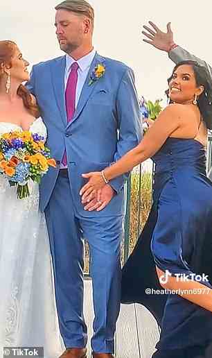 Auf einem Foto, während Braut und Bräutigam einander in die Augen starren, hält die Brautjungfer die Hand des Bräutigams