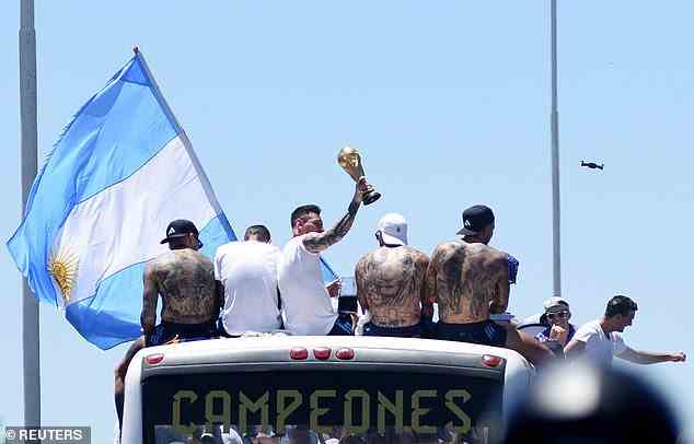 Team captain and footballing legend Lionel Messi (centre) holds the World Cup aloft to the gathered crowds