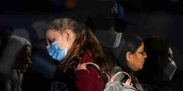 Reisende mit Gesichtsschutzmasken warten am Montag, 19. Dezember 2022, in der Schlange, um am Los Angeles International Airport in Los Angeles einzuchecken. 