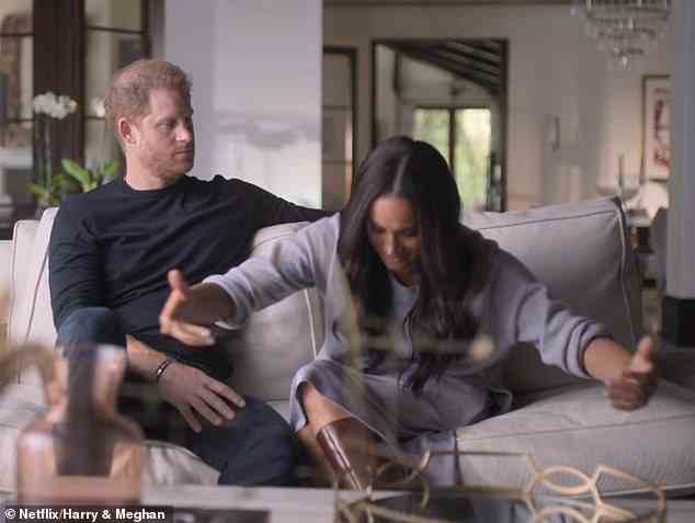 Meghan appears to perform a deeply exaggerated curtsey recounting what it was like when she first met the Queen, while her husband Harry watches on awkwardly