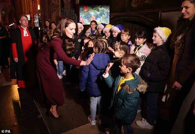Kate gives a high five to a young boy inside Westminster Abbey during her annual Christmas carol concert