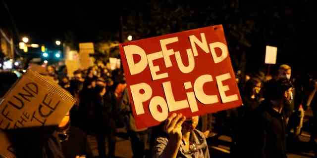 Demonstranten halten ein Schild mit der Aufschrift "Polizei enttäuschen" während eines Protestes gegen den Tod eines Schwarzen, Daniel Prude, nachdem ihm die Polizei bei einer Verhaftung am 23. März in Rochester, New York, am 6. September 2020 eine Spuckhaube über den Kopf gezogen hatte.