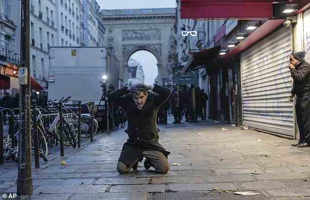A member of the Kurdish community kneels on the ground as he is detained during clashes with the police in Paris, near the site of a shooting earlier today