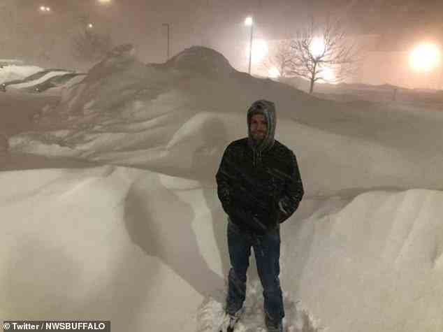 A man is seen standing among mountains of snow in Buffalo