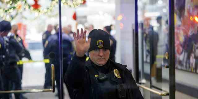 Ein Polizeibeamter aus Bloomington hält eine Hand am Eingang der Mall of America in Bloomington, Minnesota, nach Berichten über Schüsse, die am Freitag, den 23. Dezember 2022, abgefeuert wurden. 