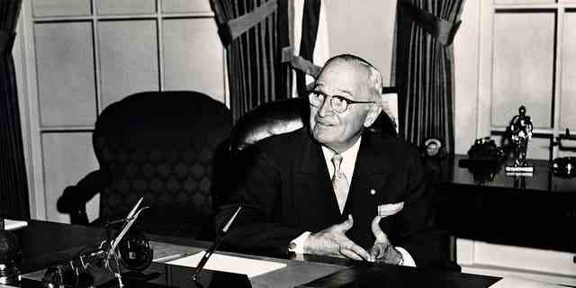 Präsident Harry S. Truman sitzt mit dem Schild im Weißen Haus "Der Dollar stoppt hier" im Vordergrund, um 1950. 