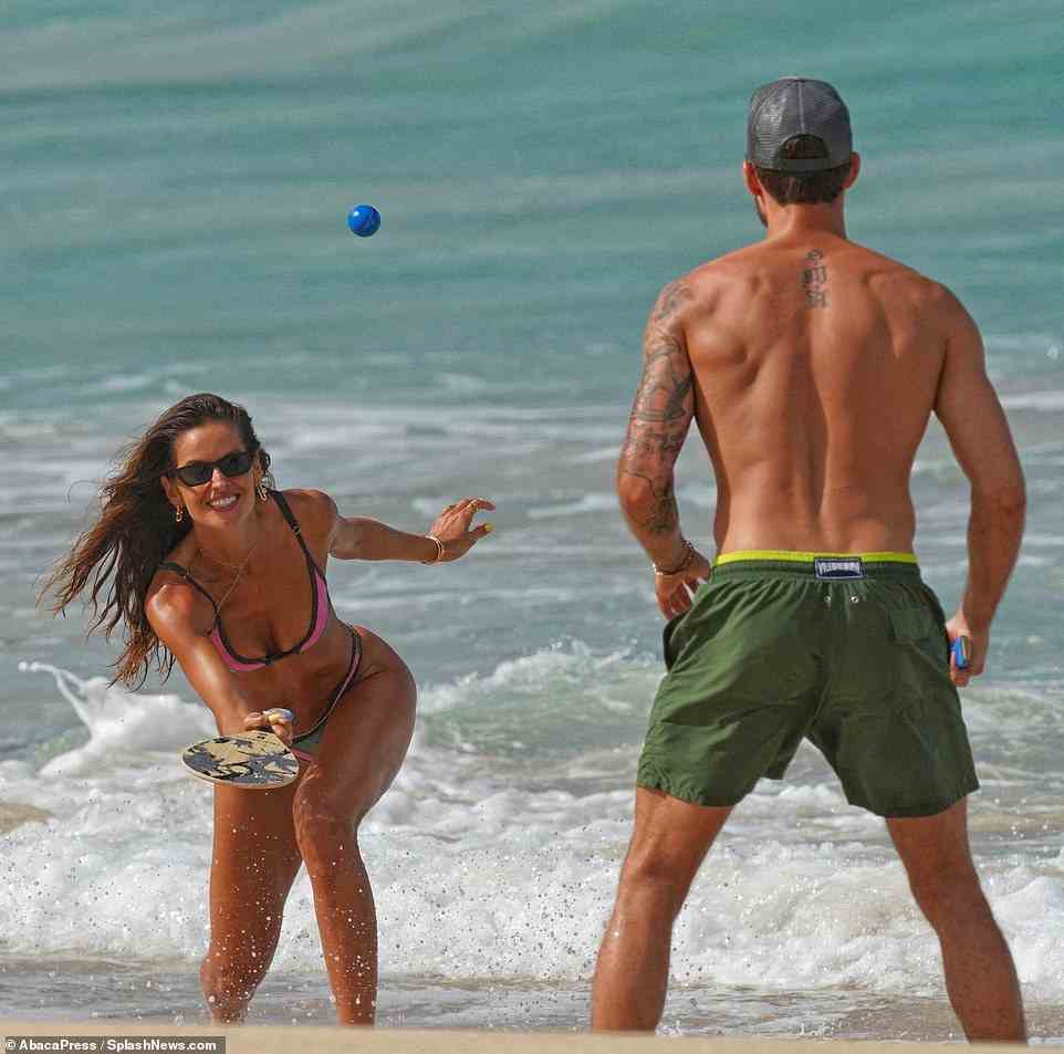 Einen Ball haben!  Sie wurden lächelnd und lachend gesehen, als sie am Strand eine Partie Tischtennis spielten