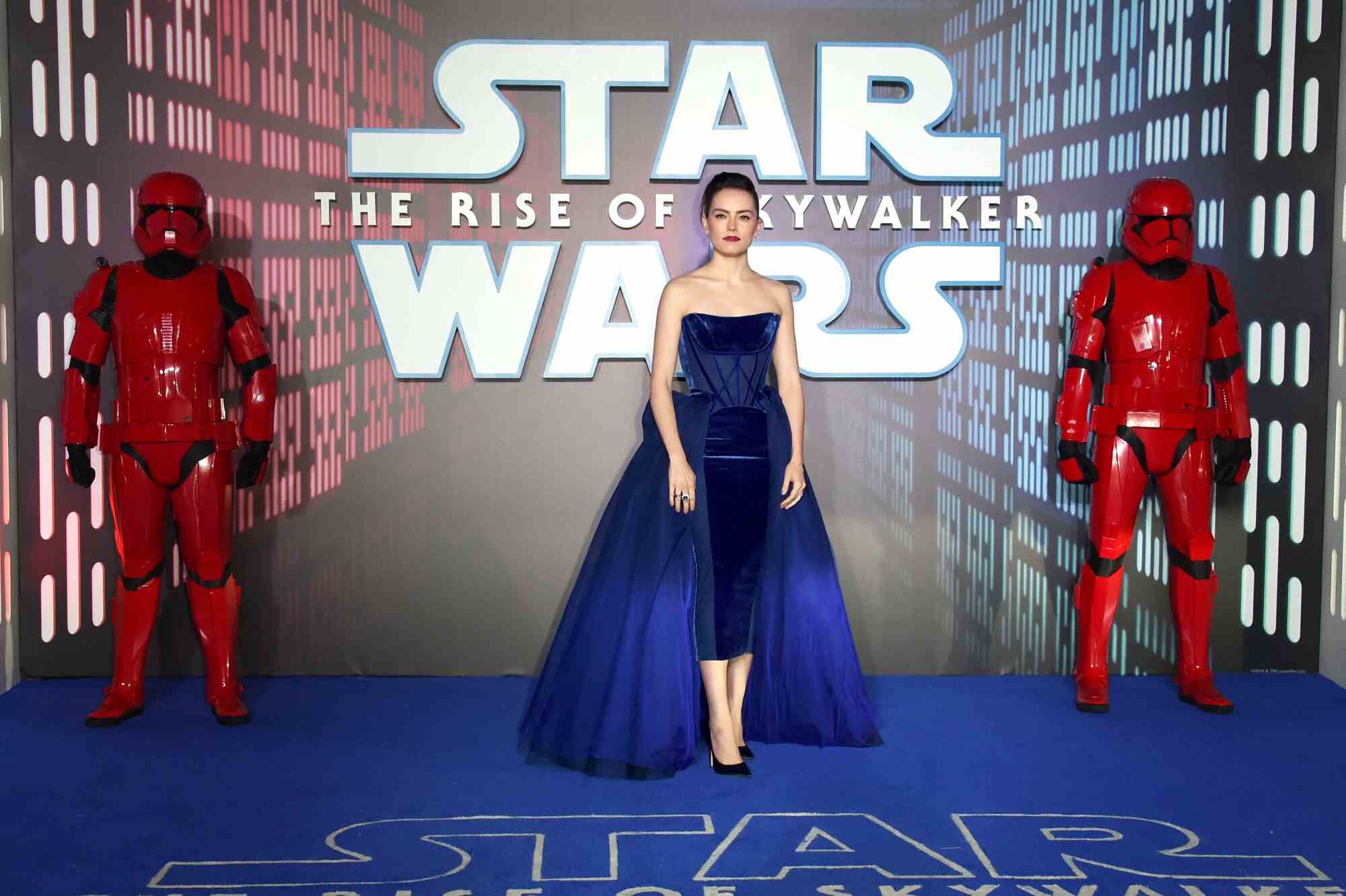 Eine dunkelhaarige Frau in einem blauen Miederkleid vor einem Star Wars-Schild.