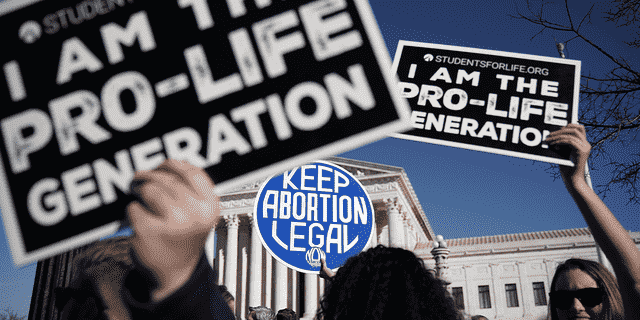 Pro-Life-Aktivisten versuchen, das Schild eines Pro-Choice-Aktivisten während des 2018 March for Life am 19. Januar 2018 in Washington, DC, zu blockieren.  EIN