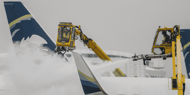 Arbeiter enteisen ein Flugzeug von Alaska Airlines während eines Schneesturms am Seattle-Tacoma International Airport in Seattle am 20. Dezember 2022.