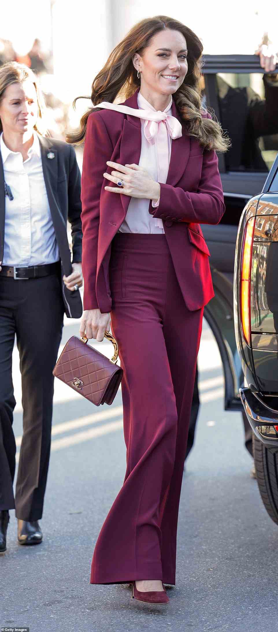 Kate Middleton continued her tour of the US in a chic $2,724 Alexander McQueen burgundy pants suit on Thursday morning, which she accessorized with a stunning $4,664 Chanel maroon and gold enamel purse
