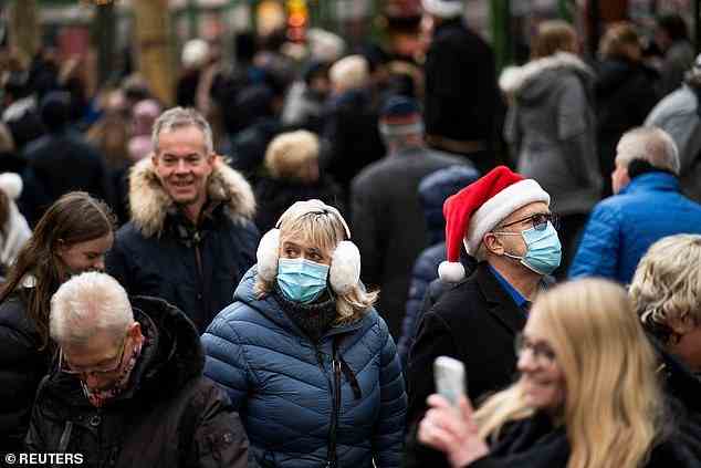 New York City officials advised residents to wear masks in indoor public places and outdoor crowded places last week. Pictured: Two people in New York City wear the face coverings while walking through a crowd on December 12
