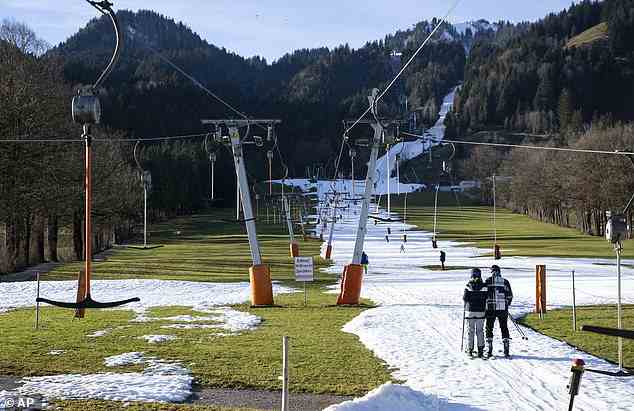 LENGGRIES, GERMANY: The unprecedented January 'heat dome' has produced temperatures ranging from 10 to 20 Celsius (50 to 68 Fahrenheit) from France to Western Russia - with several temperature records broken over the New Year weekend. Pictured: People ski up a thin sliver of snow using a T-bar lift in the German resort of Lenggries