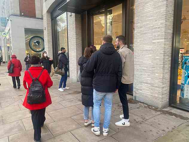 Shoppers — some wearing face masks — wait outside a Boots store in west London yesterday amid fears around the 'twindemic' of Covid and flu