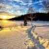 Dies zeigt einen Wanderweg durch ein schneebedecktes Feld, umgeben von Bäumen und einem wunderschönen Sonnenuntergang