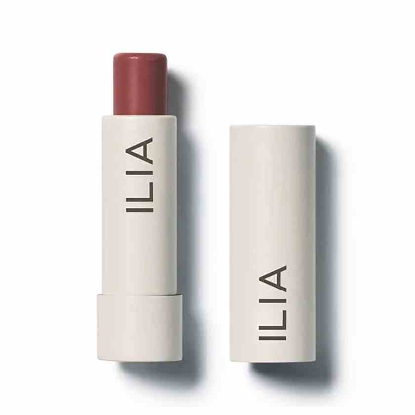 Ilia Balmy Tint Hydrating Lip Balm in Memoir beige Tube mit mauvefarbenem Lippenbalsam auf weißem Hintergrund