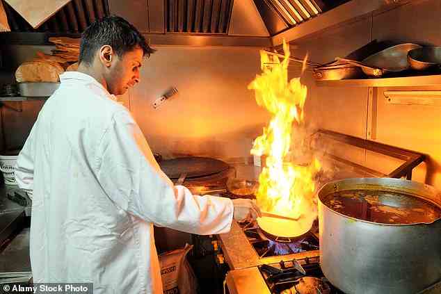 A chef cooking a balti with high burning flames at Shababs Balti in Birmingham