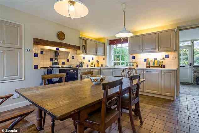 Die Küche hat steinfarbene Wand- und Unterschränke sowie einen Fliesenboden im Landhausstil
